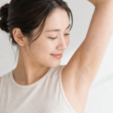 片腕を上げて脇を確認する女性